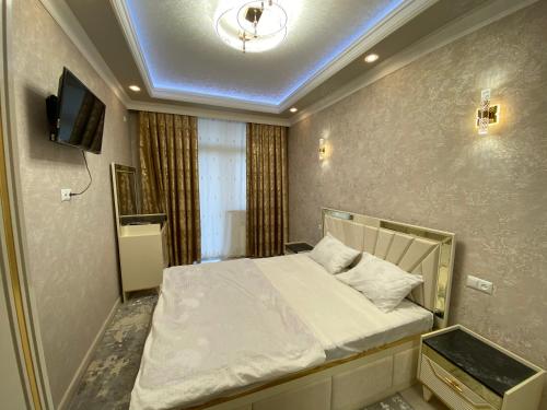 um pequeno quarto com uma cama e uma televisão em Spectre Neo Classic Cozy Home em Tashkent