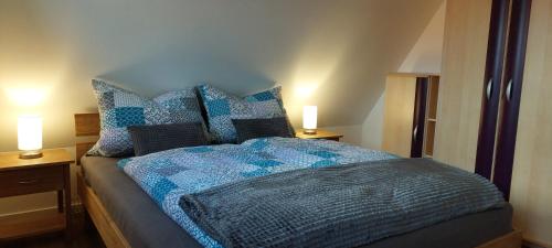 a bed with a blue comforter and two lamps on tables at Ferienwohnungen Urlaubsglück in Kurort Gohrisch