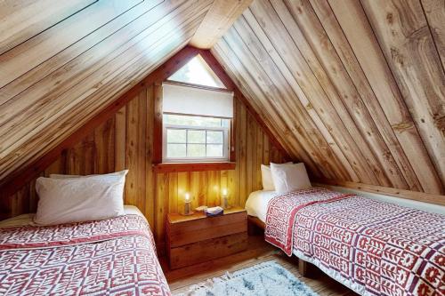 two beds in a wooden room with a window at Balsam House in Baraboo