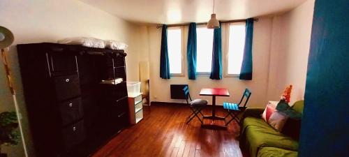 - un salon avec un canapé vert et quelques fenêtres dans l'établissement Au coeur du 18eme arrondissement proche de Montmarte et des Jeux Olympiques, à Paris