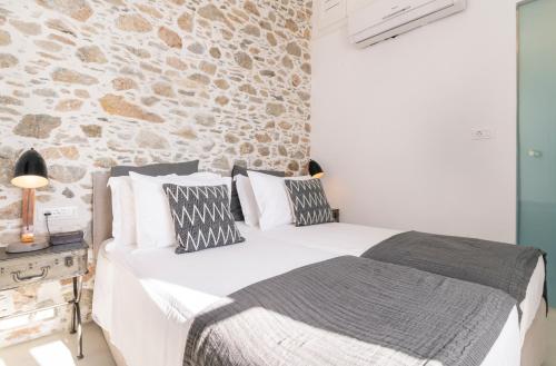 a bedroom with a white bed and a stone wall at Glaukopis Retreat in Ano Syros