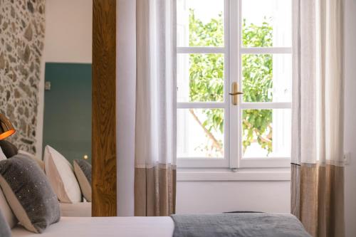 a bedroom with a window and a bed with pillows at Glaukopis Retreat in Ano Syros