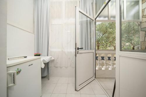 a white bathroom with a door and a window at Rooms Orion in Vodice