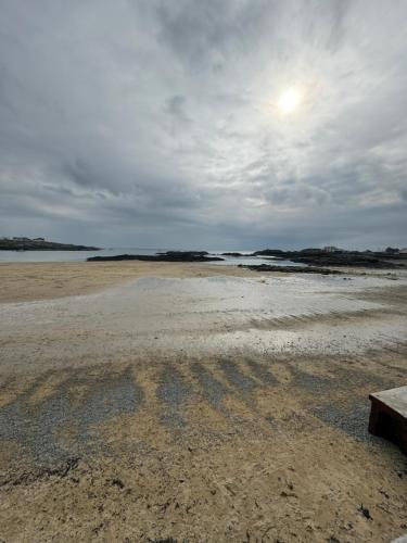 a bench sitting on top of a sandy beach at Four mile bridge by Trearddur bay in Valley