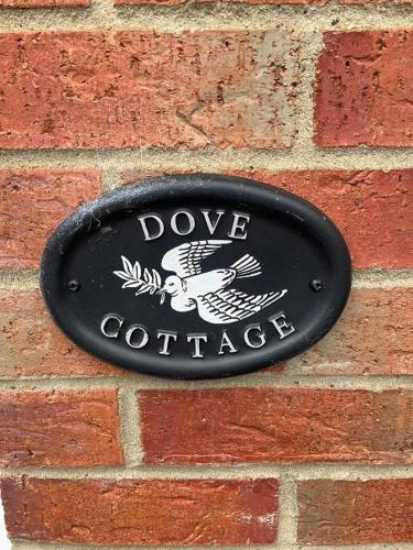 a black sign on the side of a brick wall at LetAway - Dove Cottage Pickering in Pickering
