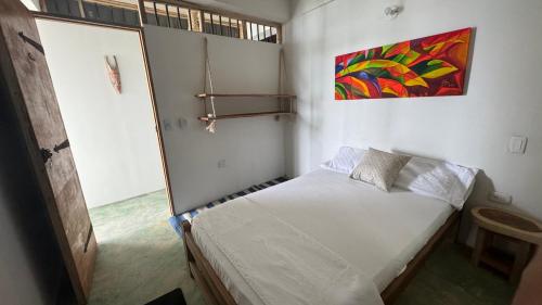 een kleine slaapkamer met een bed en een schilderij aan de muur bij Cabaña Punta Coral in Rincón
