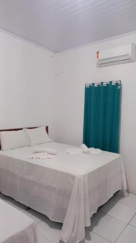 a bedroom with a bed with a blue curtain at Pousada Vela dos Ventos in Praia de Moitas