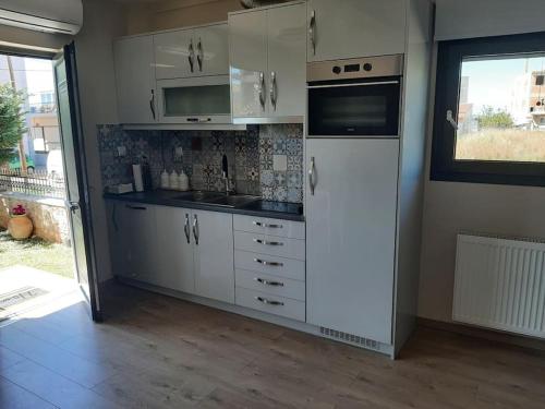 a kitchen with white cabinets and a white refrigerator at studio yannis leonidas in Asprókhoma