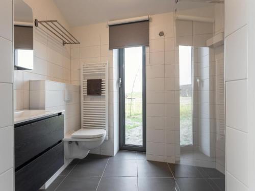 een badkamer met een toilet en een glazen deur bij Lovely house in nature in Wissenkerke