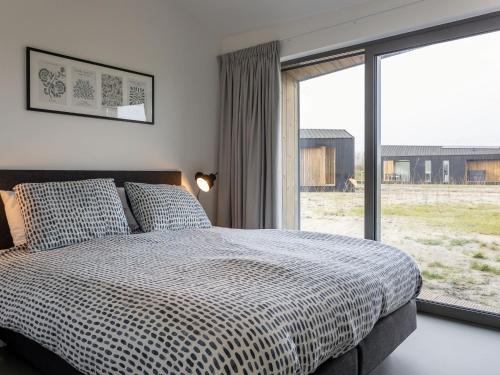 een slaapkamer met een bed en een groot raam bij Lovely house in nature in Wissenkerke