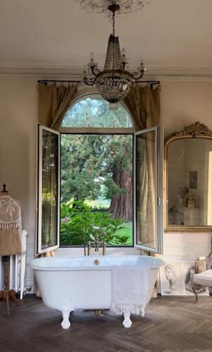 une baignoire dans une pièce avec une grande fenêtre dans l'établissement Les séquoias géants, à Saint-Martin-aux-Arbres