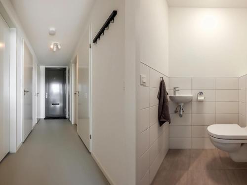 een witte badkamer met een toilet en een wastafel bij Spacious holiday home with garden in Wissenkerke