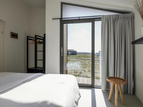 een slaapkamer met een bed en een groot raam bij Majestic holiday home with garden in Wissenkerke