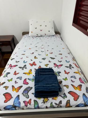 uma cama com um cobertor com borboletas em Casa da Vó Loy e seu espaço verde em Araraquara