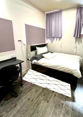 1 dormitorio con cama, escritorio y pantalla de proyección en Kings Cross Beautiful Studio en Londres