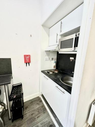 una pequeña cocina con fregadero y microondas en Kings Cross Beautiful Studio en Londres