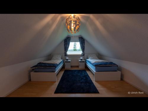 a attic room with two beds and a window at NEU! Ferienhaus am grünen Kamp in Bockhorn