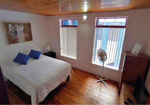 サン・ルイス・ポトシにあるDepartamento en Casa Azul centro de SLP con jacuzzi y terraza - INMOTEGAのベッドルーム1室(青い枕とファン付きのベッド1台付)