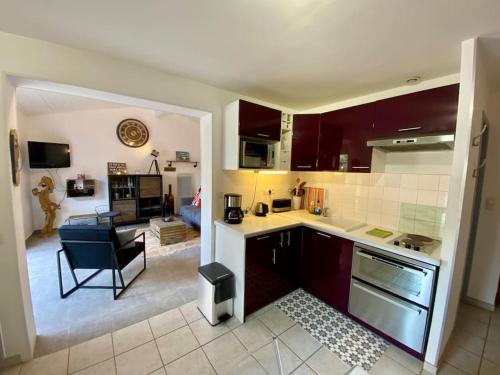 une cuisine avec des placards rouges et un salon dans l'établissement Charmante maison lacanau océan, à Lacanau-Océan