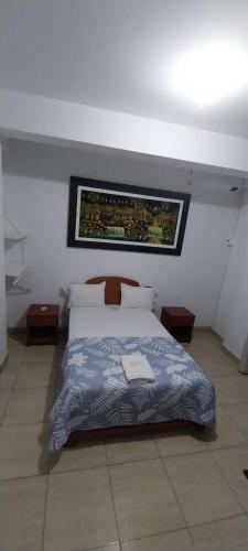 a bedroom with a bed with a painting on the wall at Hospedaje Moralillos in Yurimaguas