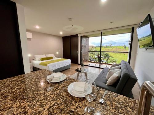 1 dormitorio con 1 cama y sala de estar con mesa en Hotel Rioverde en Rionegro