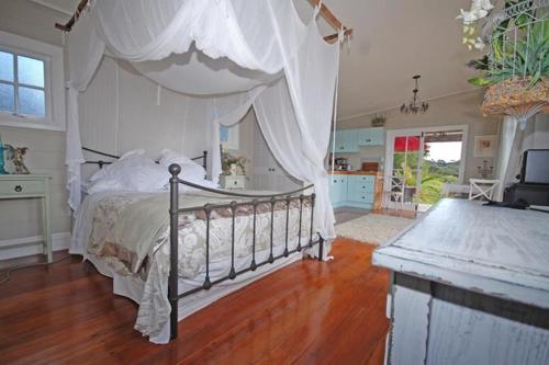 a bedroom with a bed with a canopy at Freshwaterfarm Cottages - Muriwai in Waimauku