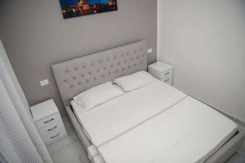 a small bedroom with a white bed with two night stands at Vila Stefano Stepa in Tragjas