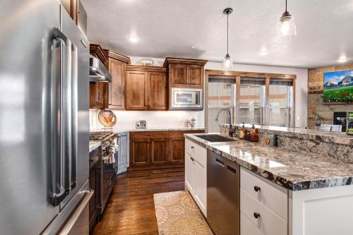 eine Küche mit Holzschränken und einem Kühlschrank aus Edelstahl in der Unterkunft Village at the Shores 201 by Moose Management in Cranmer