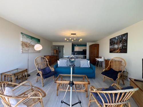 un salon avec un canapé bleu et des chaises dans l'établissement Appt traversant vu Mer et Dunes avec Garage, à Le Touquet-Paris-Plage