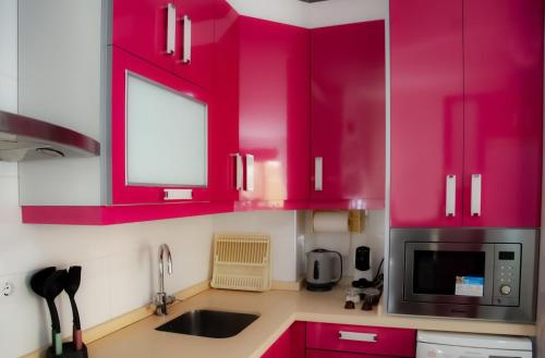 La cuisine est équipée de placards rouges, d'un évier et d'un four micro-ondes. dans l'établissement Apartamento El Zapillo III, à Almería