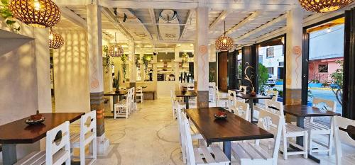 a restaurant with wooden tables and white chairs at Casa Oro Eco Hostel in San Juan del Sur