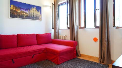 a red couch in a living room with windows at L' appartamento sul Naviglio in Milan