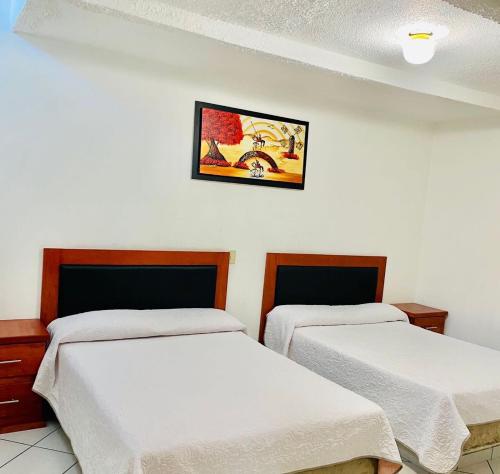 um quarto com duas camas e uma foto na parede em Posada Mi Rey em Guadalajara