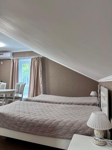 a bedroom with two beds and a table with a lamp at Hotel Korona in Kropyvnytskyi