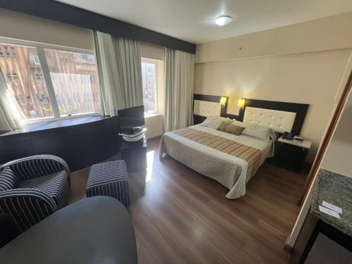 um quarto com uma cama, 2 janelas e um sofá em UH 110 Flat Hotel Rua Maestro Cardim - Bela Vista em São Paulo