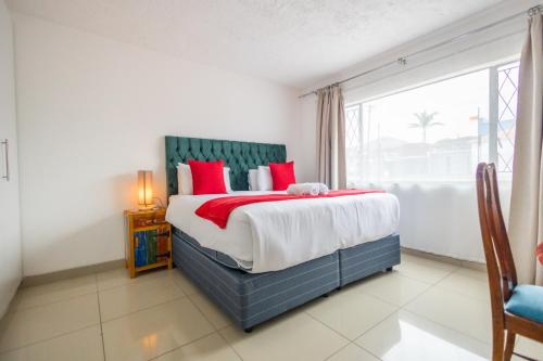 a bedroom with a bed with red pillows and a window at Safi Luxury Apartment - 3 in East London