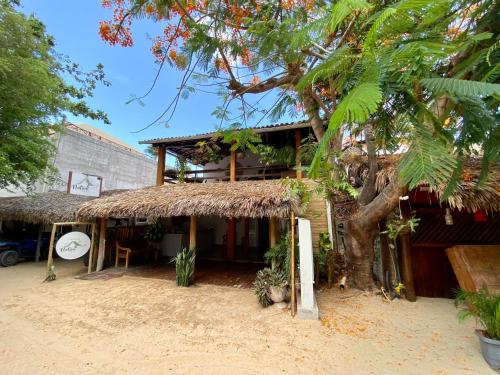 un bâtiment avec un toit de paille et un arbre dans l'établissement Pousada Nativa Jeri, à Jericoacoara