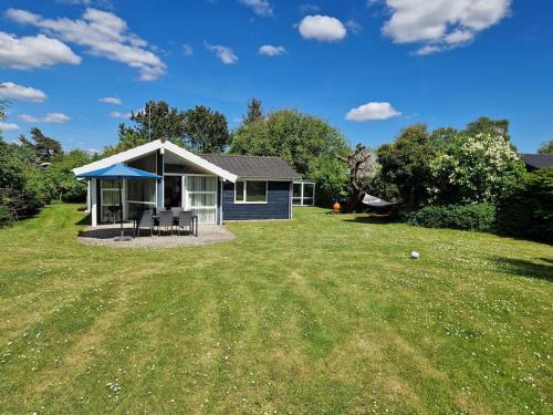 a small blue house in the middle of a yard at Holiday house by a fantastic beach and free WiFi in Slagelse