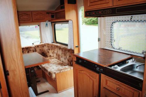 an rv kitchen with a sink and a couch at WOODMOOD Caravan Experience in Leuk