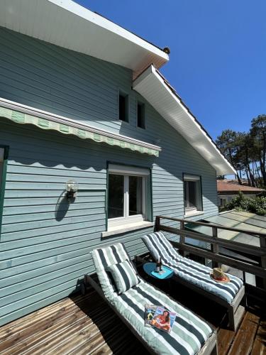 une terrasse avec deux chaises longues et une maison dans l'établissement Maison de vacances à Lacanau, à Lacanau