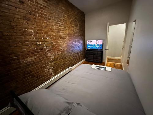 a bedroom with a bed and a brick wall at Cozy Townhouse in Harlem in New York