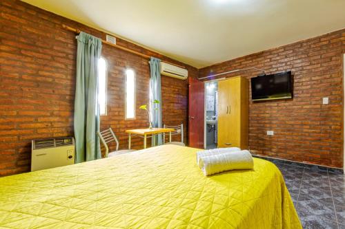 een slaapkamer met een geel bed en een bakstenen muur bij Nuevo Hotel Carmel in Villa Parque Siquiman