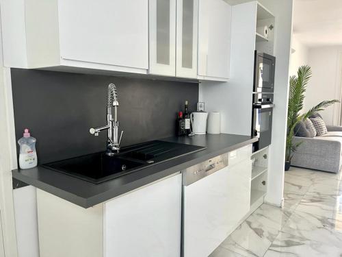 La cuisine est équipée de placards blancs et d'un évier noir. dans l'établissement Superbe appartement à Cannes / 3 chambres, à Cannes