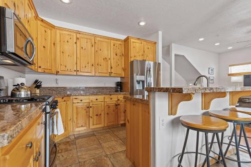 kuchnia z drewnianymi szafkami i stołkami barowymi w obiekcie Bear Hollow Village 5519 by Moose Management w mieście Park City