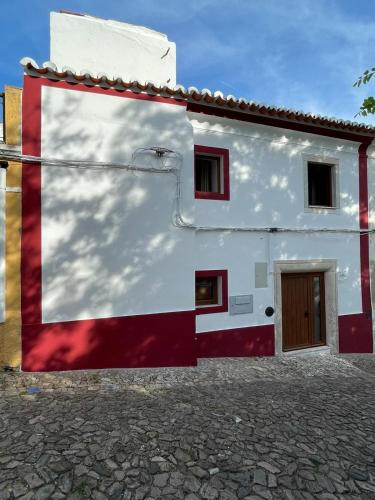 a white building with red and white paint on it at Casa da Abobereira in Estremoz