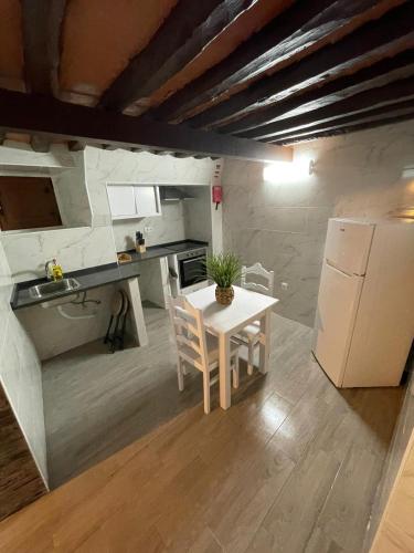 a small kitchen with a table and a white refrigerator at Casa da Abobereira in Estremoz