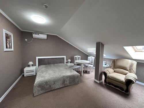 ein Schlafzimmer mit einem Bett, einem Stuhl und einem Tisch in der Unterkunft Hotel Korona in Kropywnyzkyj