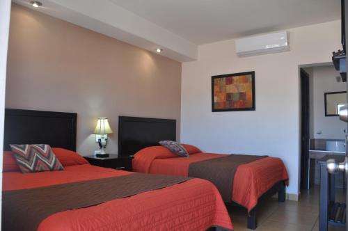 ein Hotelzimmer mit 2 Betten mit roter Bettwäsche in der Unterkunft Hotel Los Valles in Creel