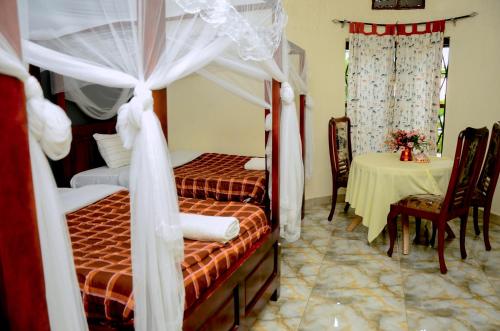 a bedroom with two beds with curtains and a table at Gorilla African Guest House in Entebbe