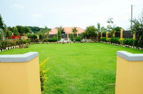 a large yard with a green lawn with a fence at Alice Gardens & Campsite in Entebbe